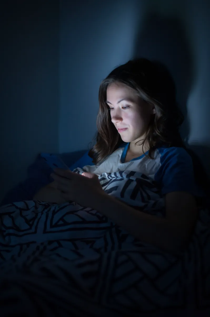 a young girl lies at home on a bed in the dark wit utc