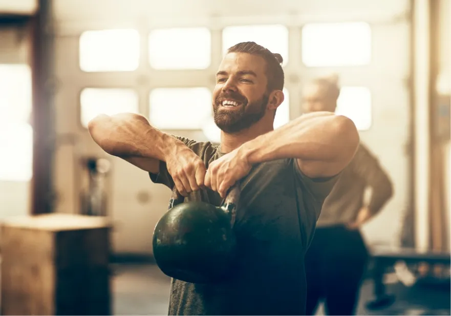 smiling young man lifting a dumbbell while working utc