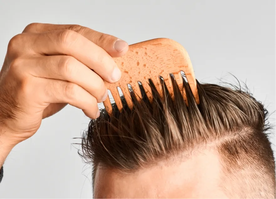 young man styling his hair with a wooden comb hai utc