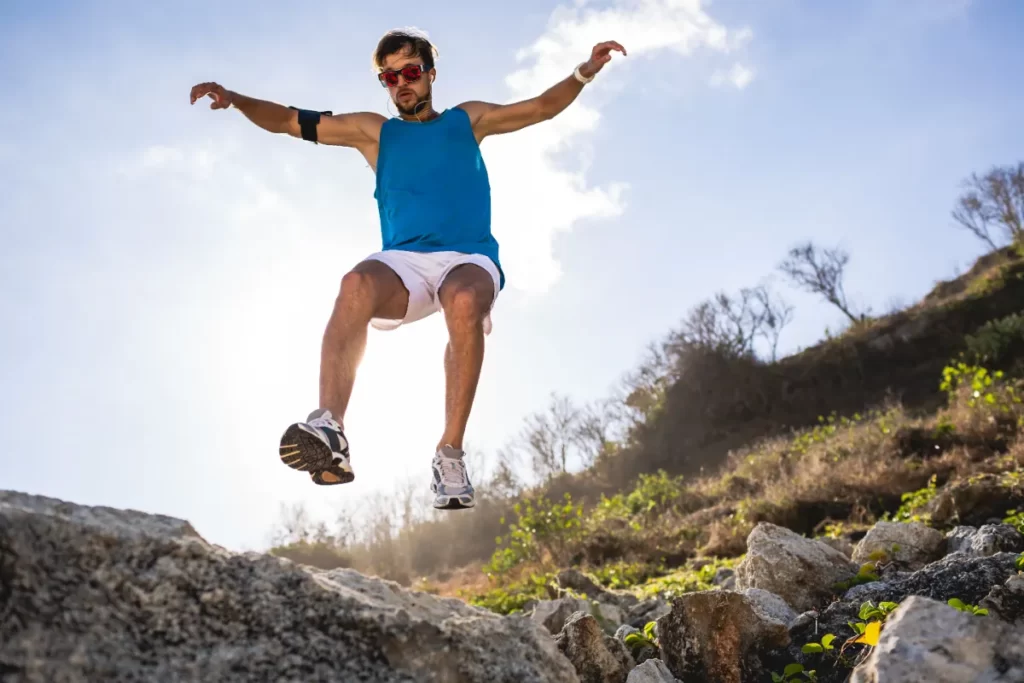 bottom view of athletic man jumping from rocks wit utc
