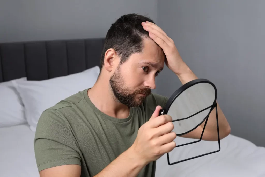 man examining hairline in mirror at home utc