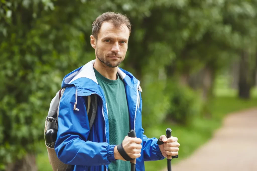 man hiking in forest with trekking poles utc